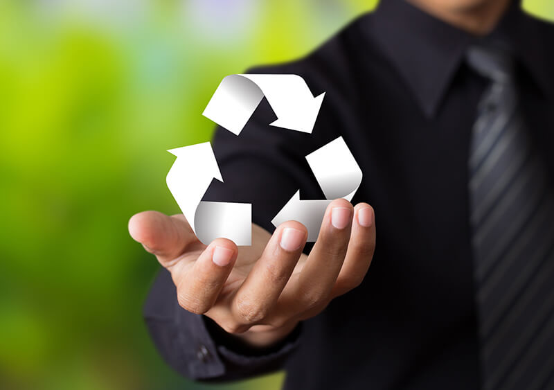 Image of man’s hand holding recycling symbol